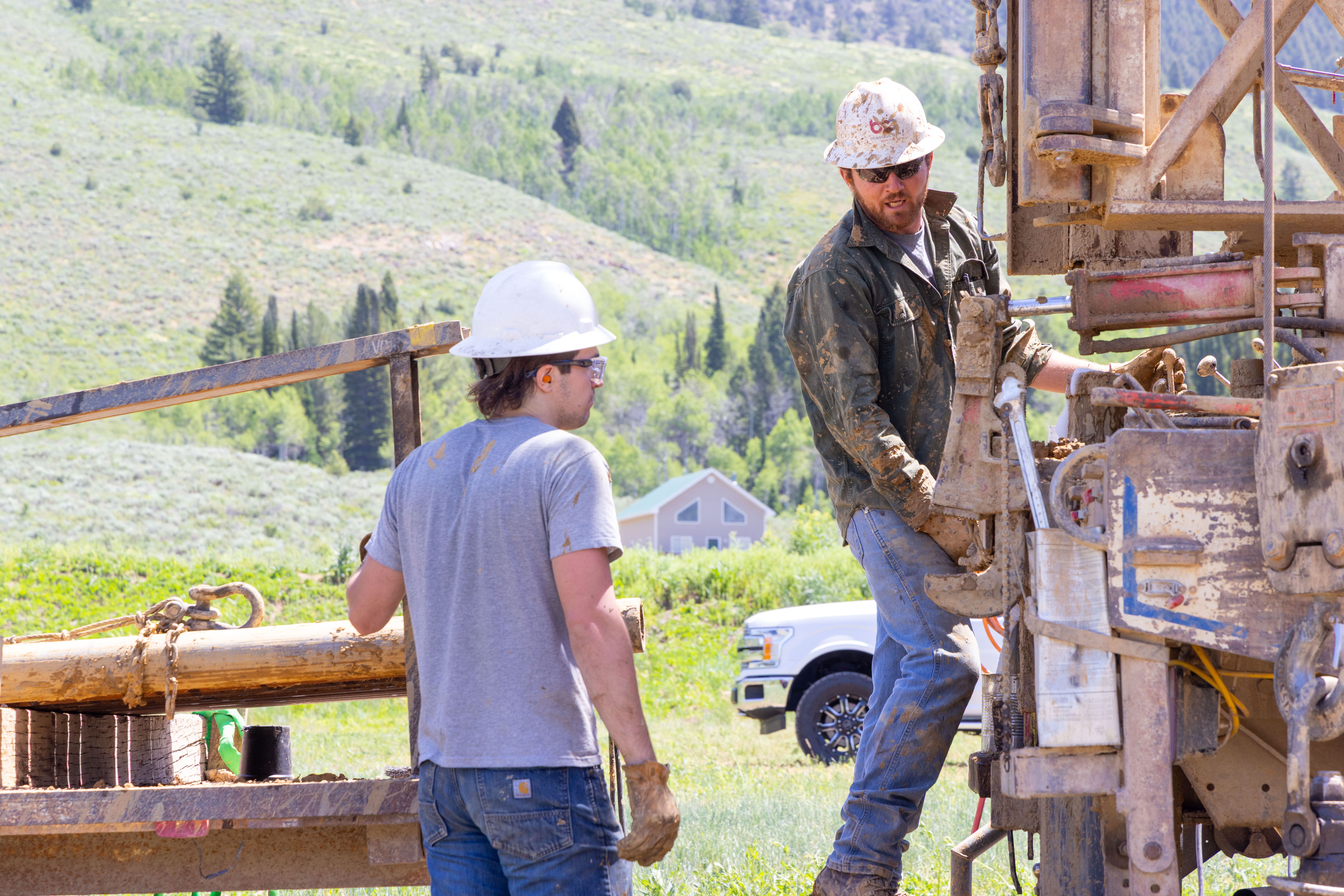 Water well drilling crew operating a drilling rig on a rural property near Bear Lake, Utah, installing a residential water well system for a cabin or home.